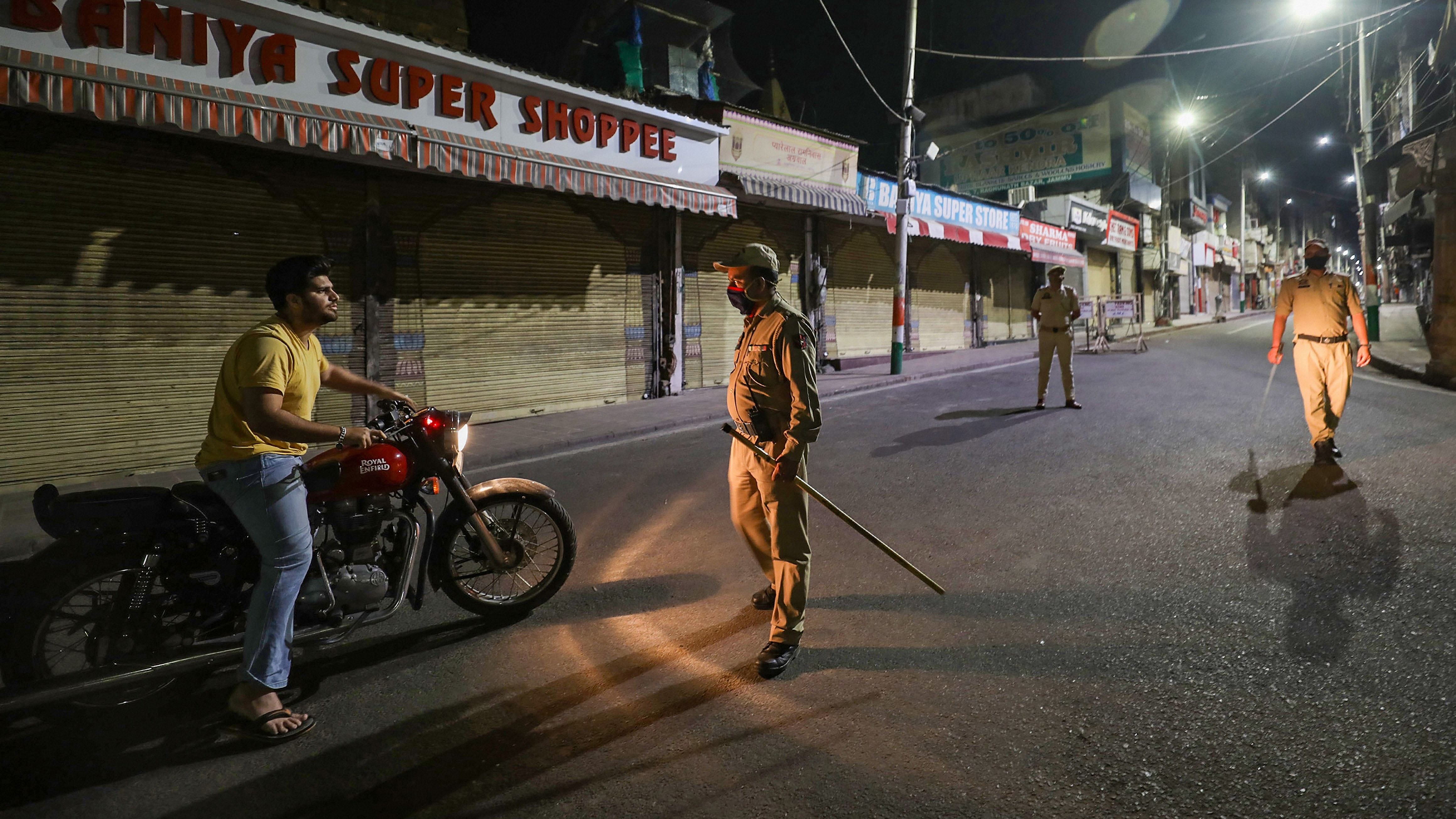 Police personnel stop the vehicle during a night curfew imposed in the wake of coronavirus pandemic, amid a countrywide spike in coronavirus cases, in Jammu. Credit: PTI File Photo
