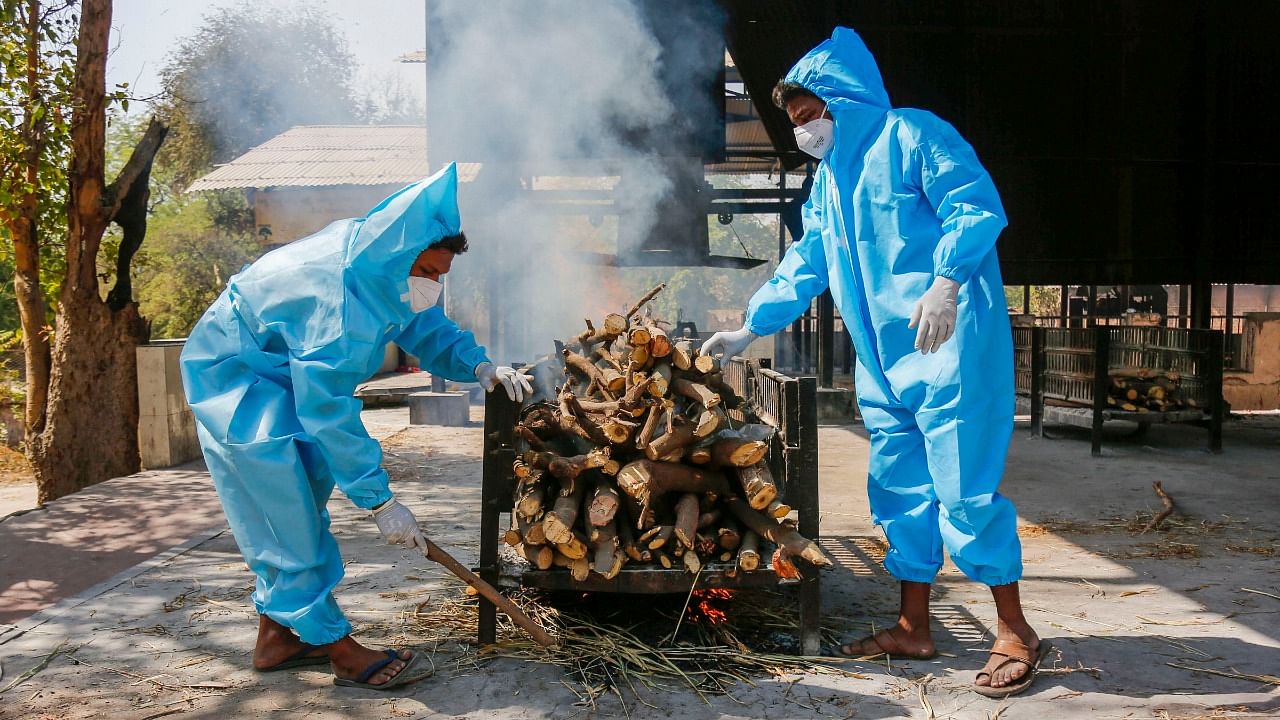 Frontline workers in personal protective equipment (PPE), arrange a funeral pyre for Covid-19 victim at a crematorium, in Ahmedabad. Credit: PTI Photo