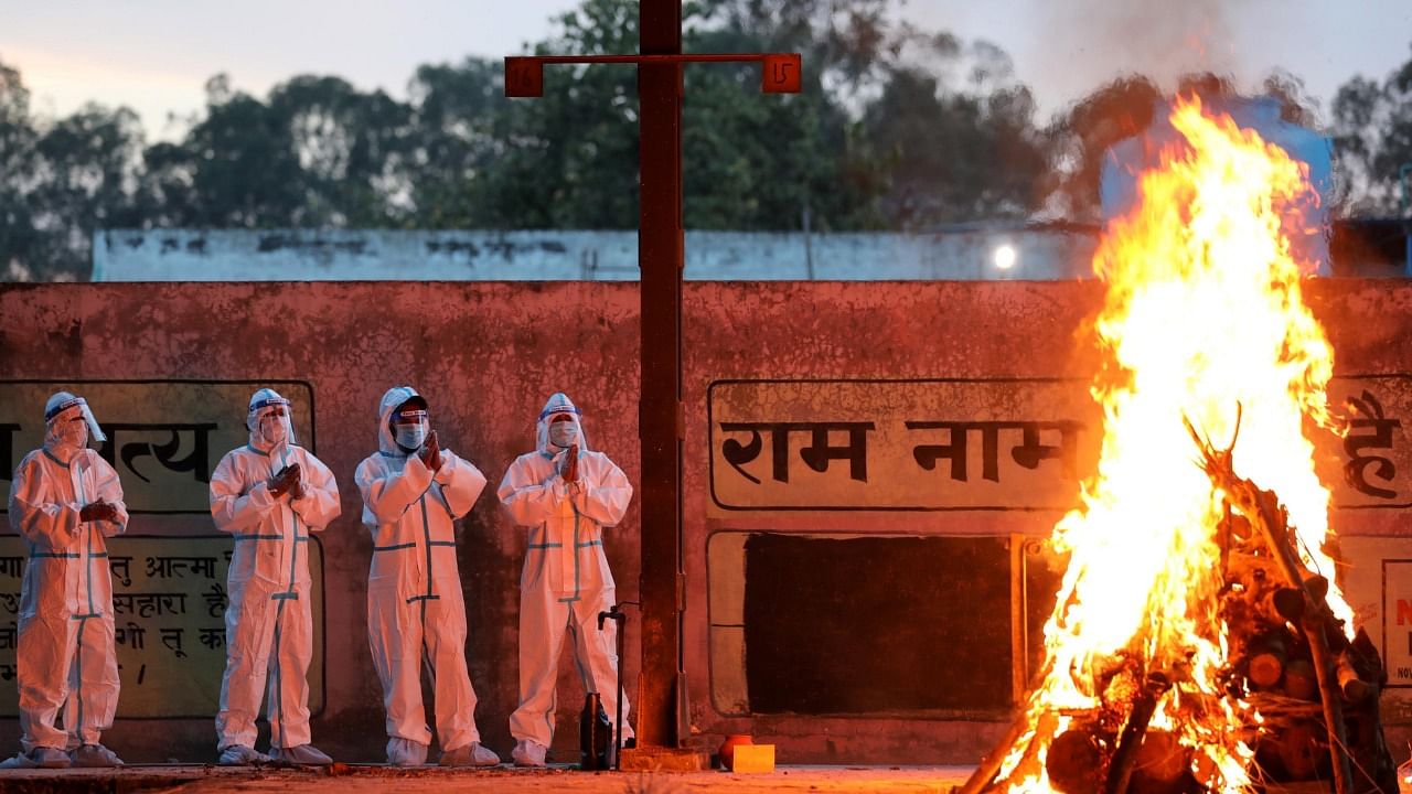 Health workers and family members, wearing protective suits, perform the last rites of a person who died of Covid-19, at Cremation Ground in Jammu, Monday, April 19, 2021. Credit: PTI Photo