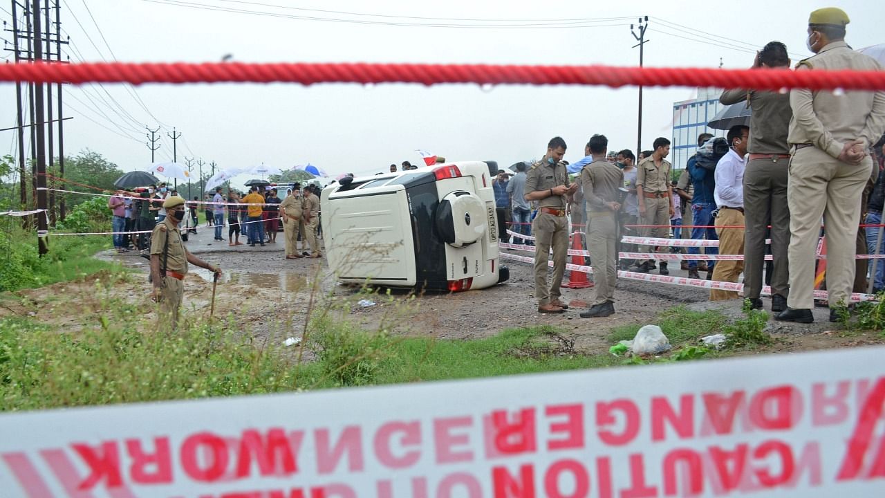 Policemen stand guard next to an overturned vehicle after the gangster Vikas Dubey was shot dead by police, on a highway at Sachendi in Uttar Pradesh. Credit: AFP File Photo