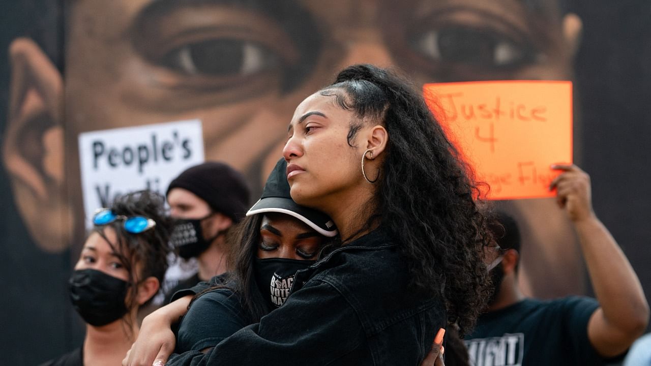 Two women embrace in front of a mural of George Floyd following the guilty verdict the trial of Derek Chauvin on April 20, 2021, in Atlanta, Georgia. Credit: AFP Photo