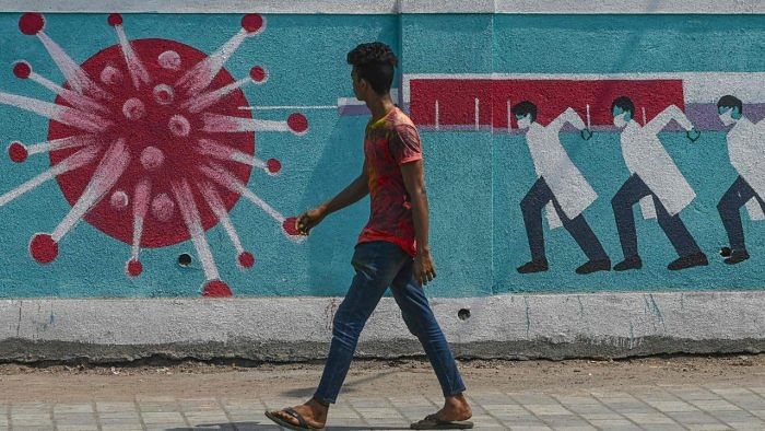 A pedestrian walks past a wall mural depicting medical staff as frontline Covid-19 warriors, in Mumbai. Credit: AFP Photo