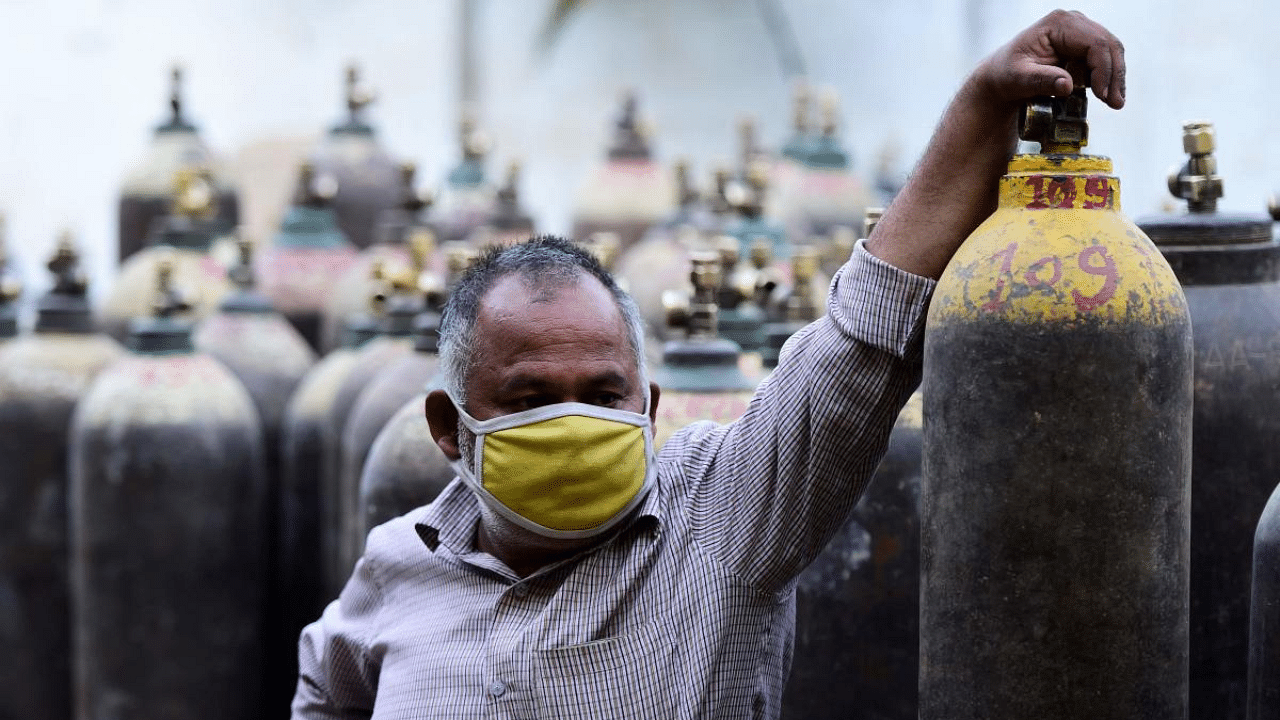 A man waits to refill a medical oxygen cylinders for a Covid-19 patient at an oxigen refile station in Allahabad. Credit: AFP photo. 