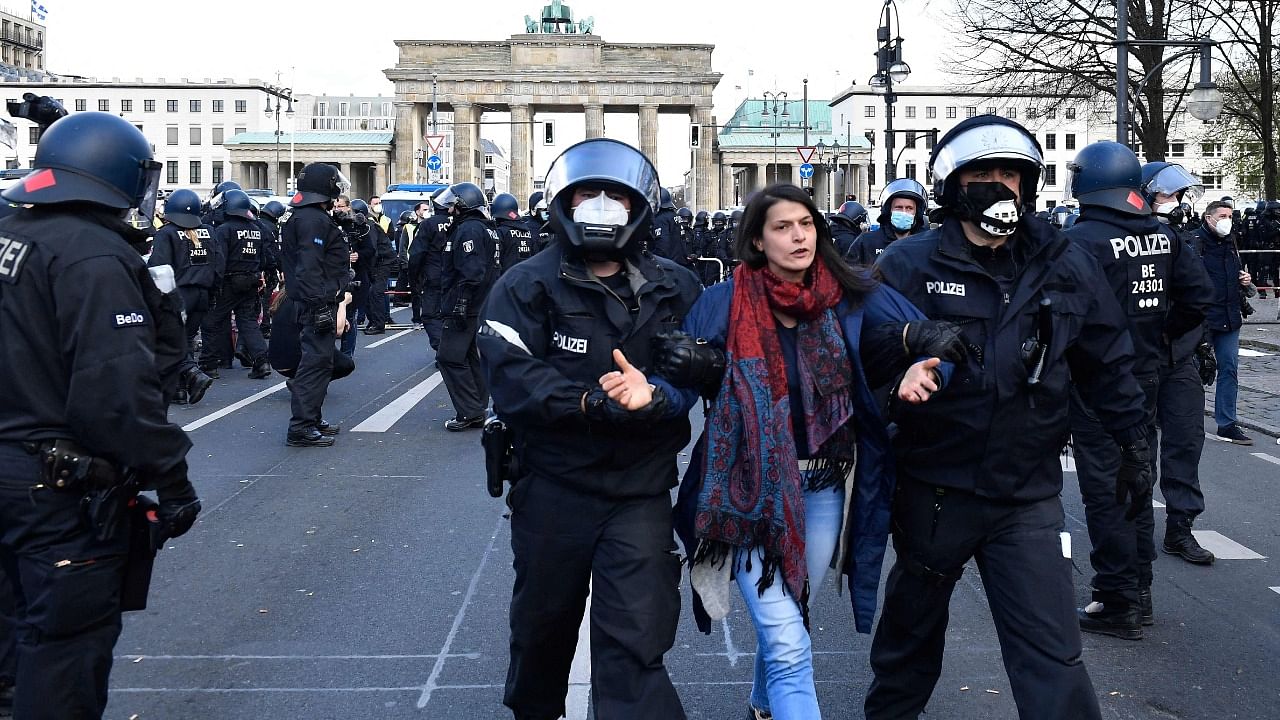 Policemen walk off a protester during a demonstration against restrictions implemented by the government in order to limit the spread the coronavirus, in Berlin on April 21, 2021, amid the novel coronavirus pandemic. Credit: AFP photo