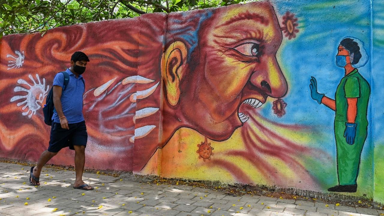 A pedestrian walks past a mural depiciting a health worker stopping the Covid-19 coronavirus, in Mumbai on April 21, 2021 amidst rising coronavirus cases. Credit: AFP photo