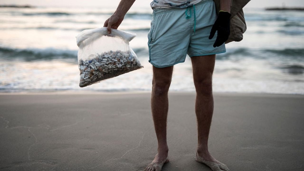 Julian Melcer holds a plastic bag filled with cigarette butts he collected from the shore of the Mediterranean Sea as part of environmental campaign, at a beach, in Tel Aviv, Israel. Credit: Reuters Photo