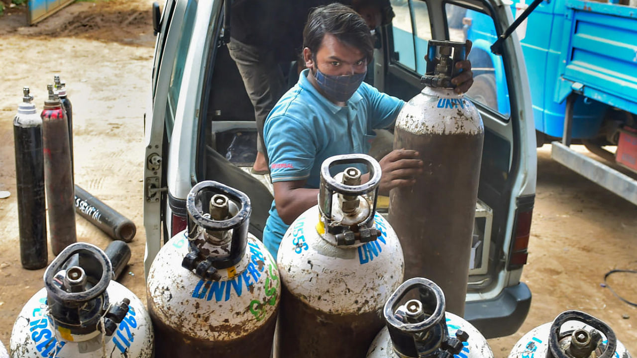 Workers sort medical oxygen cylinders meant for Covid-19 patients, before dispatching them to hospitals, amid surge in coronavirus cases, at BMTC bus stand in Bengaluru. Credit: PTI photo.