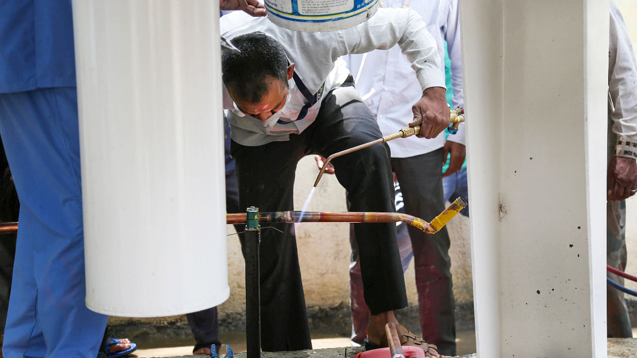 A worker welds a pipe to stop leakage of Medical oxygen gas from a storage unit, which led to interruption in supply of oxygen to Covid-19 patients in Nashik. Credit: PTI Photo