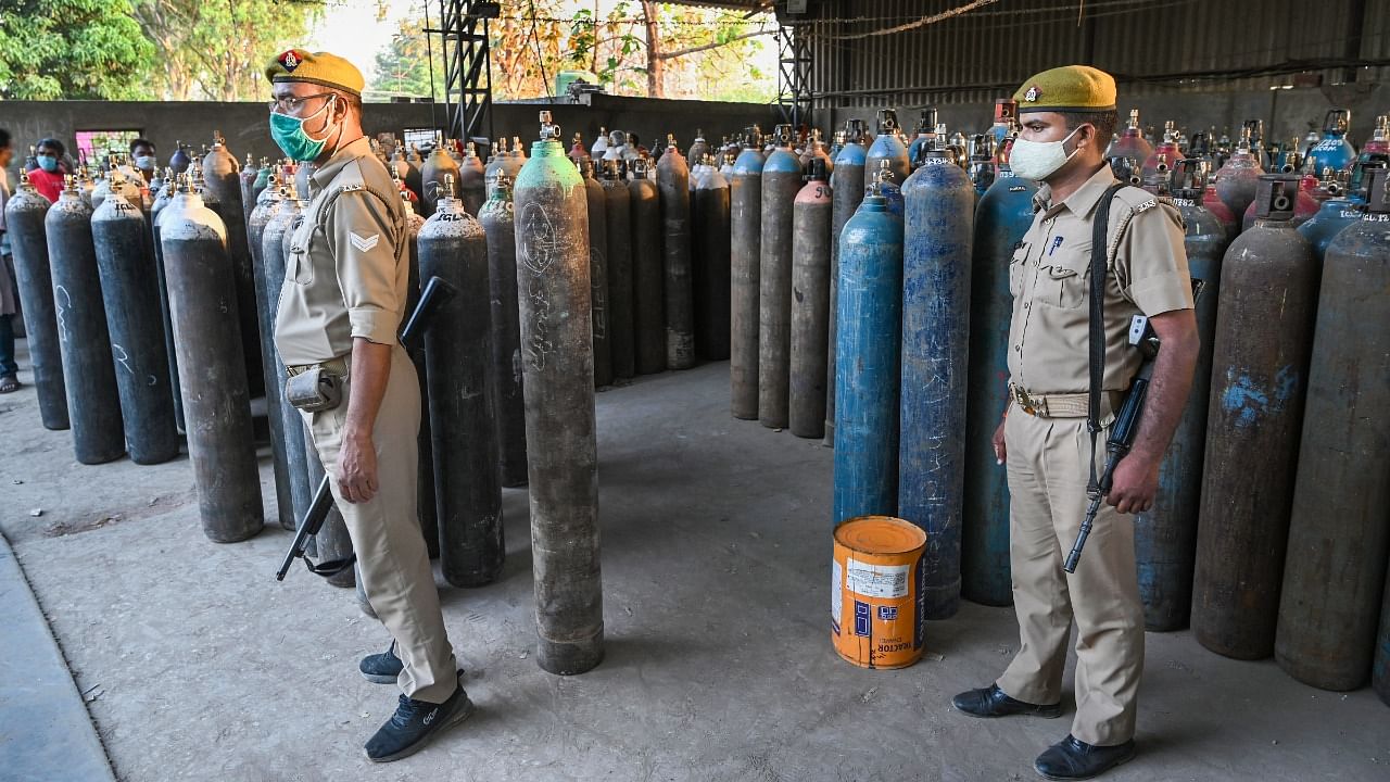 Policemen keep vigil as family members of Covid-19 patients wait to fill their empty cylinders with medical oxygen outside an oxygen filling center, as demand for the gas rises due to spike in coronavirus cases, in Prayagraj. Credit: PTI photo