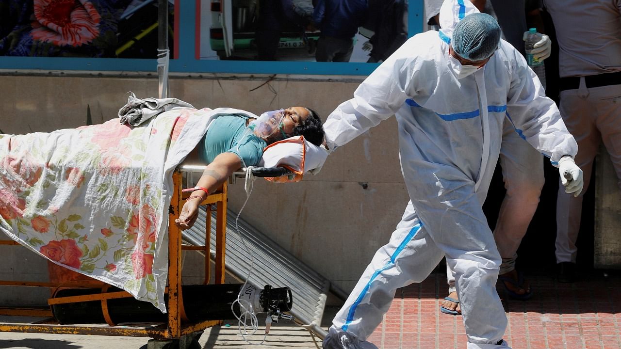 A health worker wearing personal protective equipment (PPE) carries a patient suffering from Covid-19 outside the casualty ward at Guru Teg Bahadur hospital, in New Delhi. Credit: Reuters photo