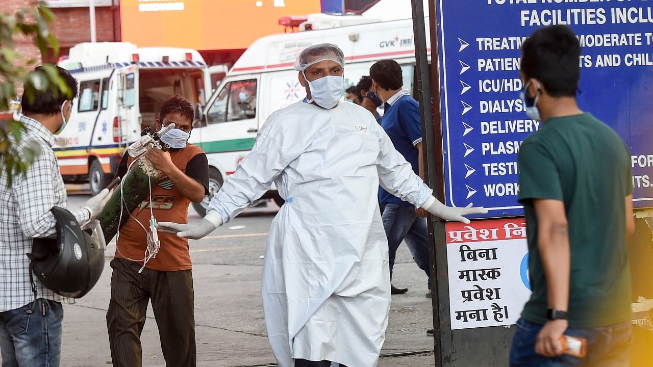 A security person stops people due to non availability of beds at LNJP Hospital, in New Delhi. Credit: PTI