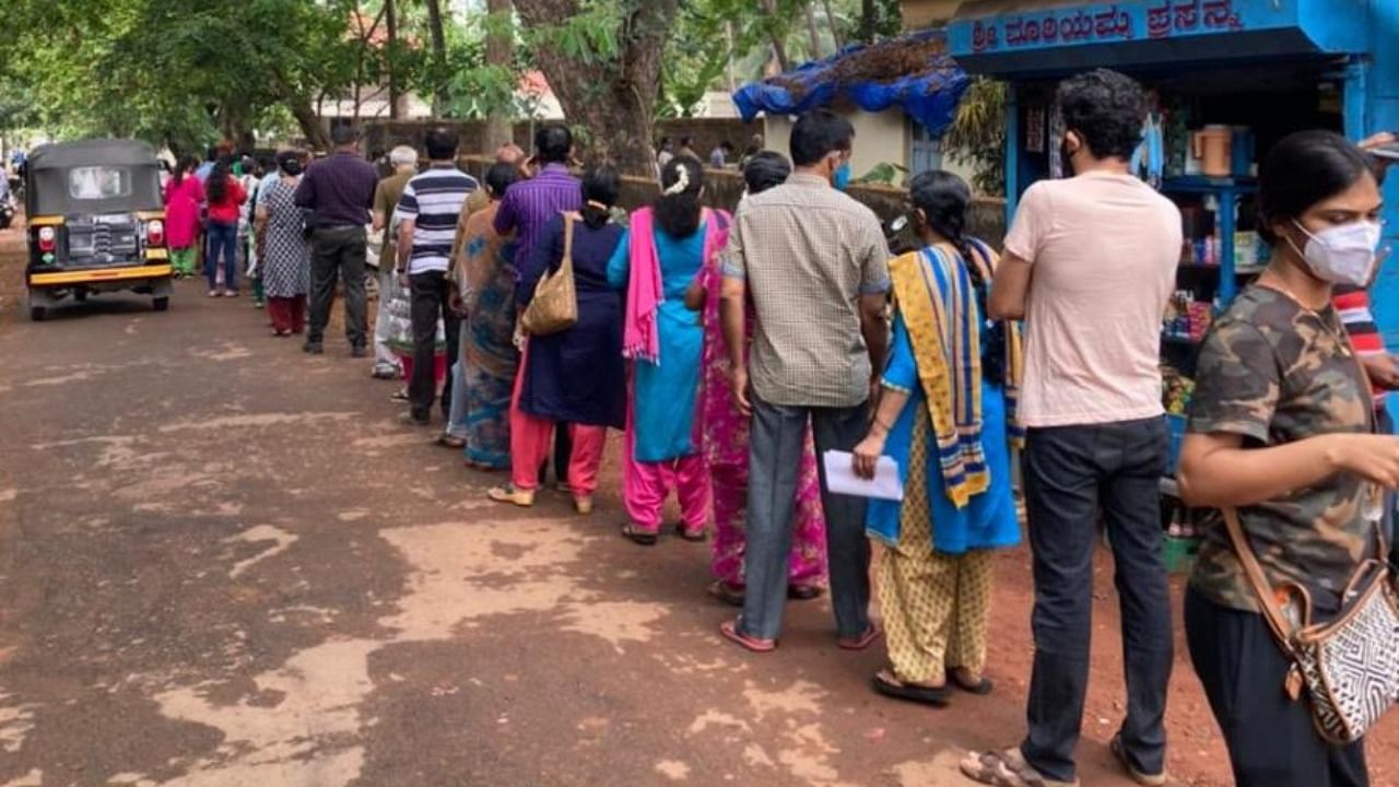 People wait in a queue outside a vaccination centre in Mangaluru on Saturday. Credit: DH Photo