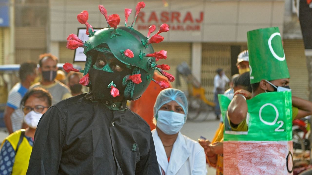 A man from a NGO wearing an outfit resembling the Covid-19 coronavirus moves around a marketplace urging people to follow the safety protocols during an awareness drive held in Siliguri on April 25, 2021. Credit: AFP Photo