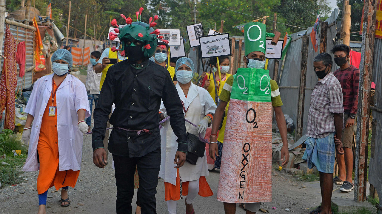 A man from an NGO wearing an outfit resembling the Covid-19moves around a marketplace urging people to follow the safety protocols during an awareness drive held in Siliguri. Credit: AFP Photo