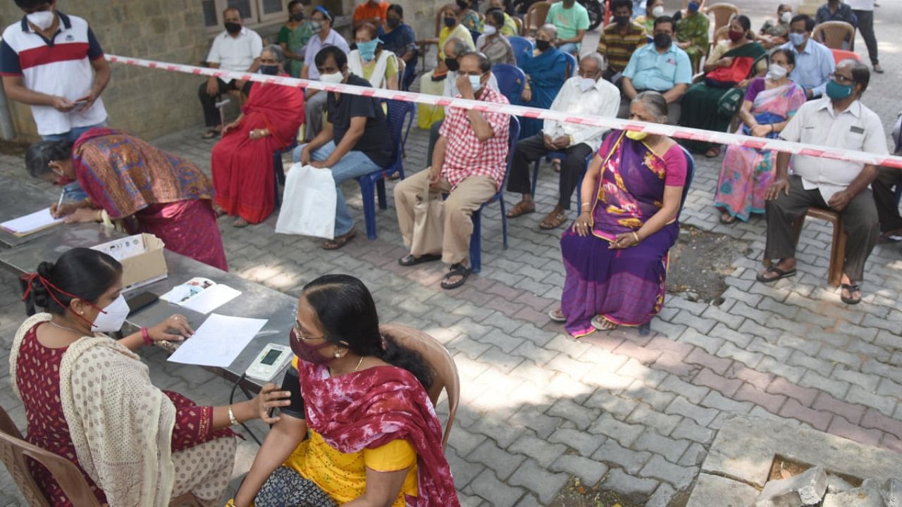 People wait for their turn to take Covid vaccine at government hospital in NR Colony, Bengaluru on Sunday. Credit: DH Photo/S K Dinesh