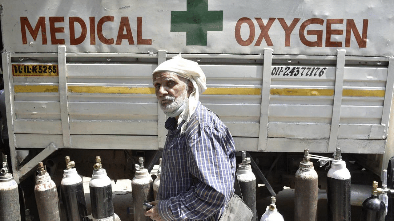 A relative of a Covid-19 patient waits to refill cylinders with medical oxygen, in New Delhi. Credit: PTI photo.