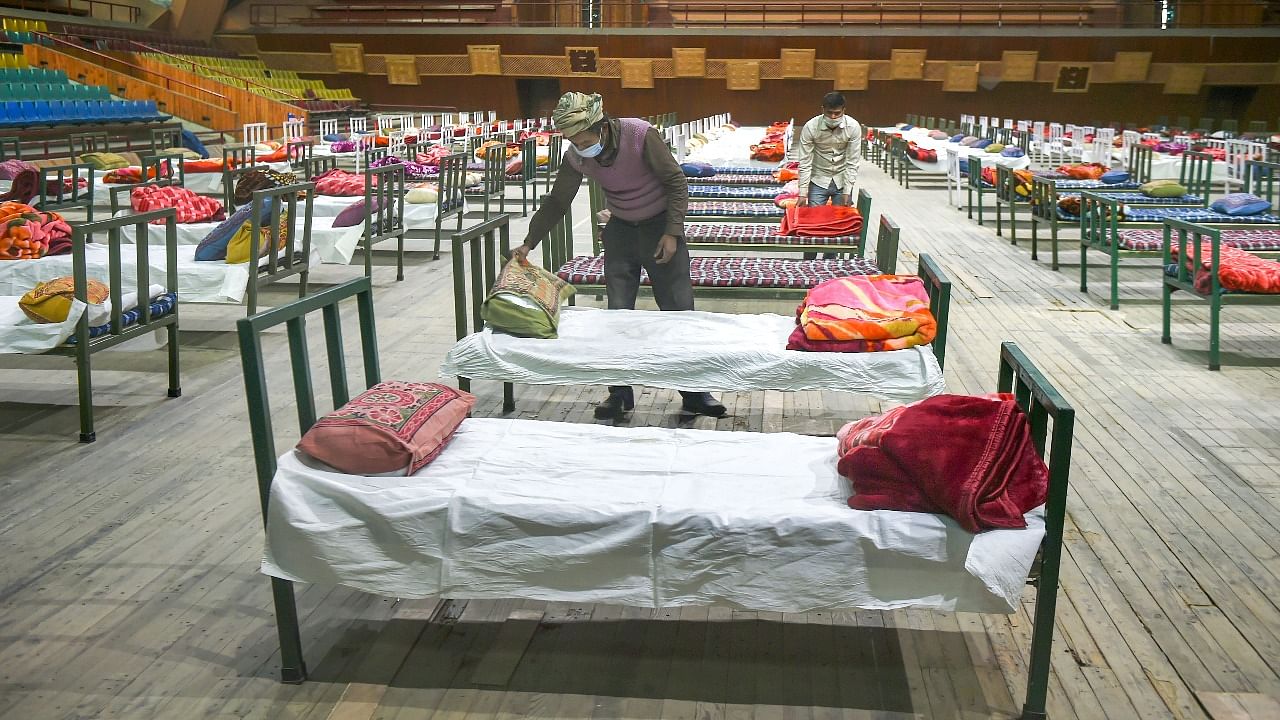 Workers during preparations to convert an indoor stadium into Covid-19 centre for an emergency in the wake of the spike in the number of positive cases, in Srinagar. Credit: PTI photo