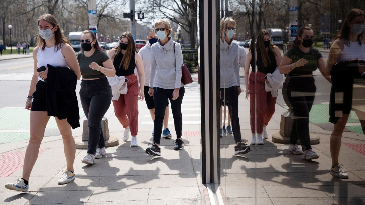 A group of people walk wearing protective masks head to a restaurant as Covid-19 restrictions are eased in Ann Arbor, Michigan, US. Credit: Reuters File Photo