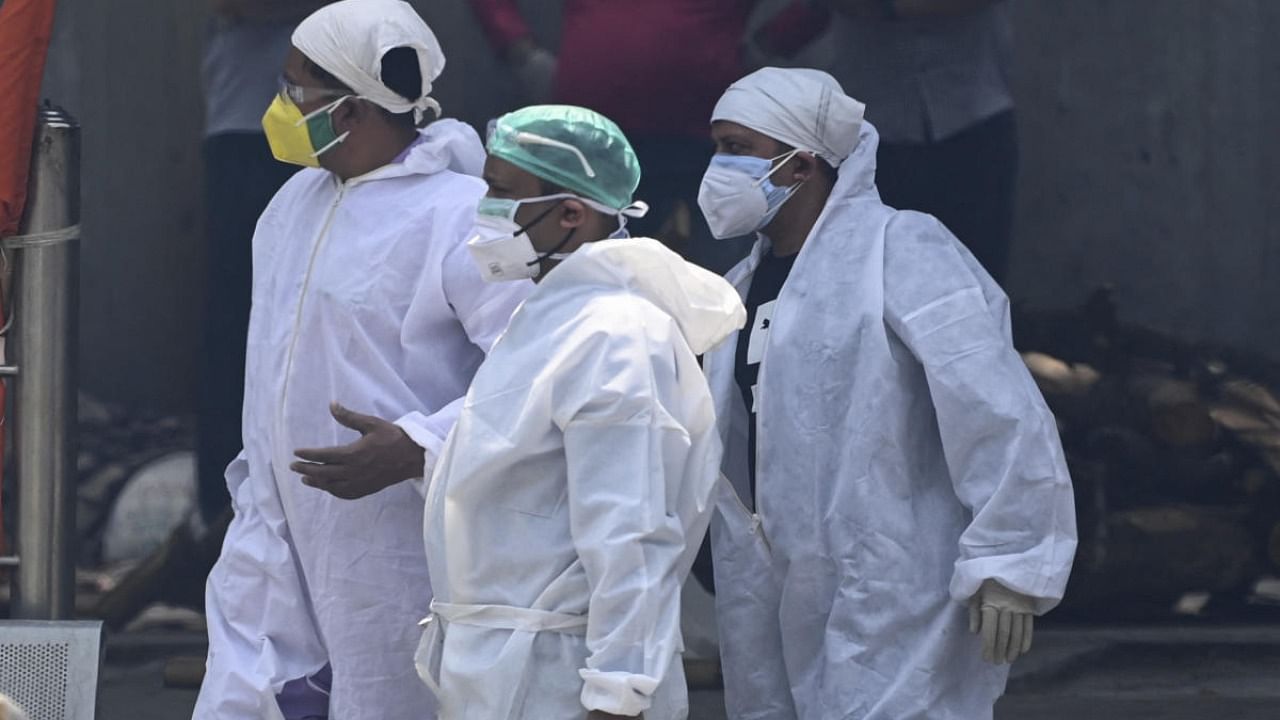 People in a personal protective equipment (PPE) during the cremation of a relative who died of the Covid-19. Credit: AFP Photo