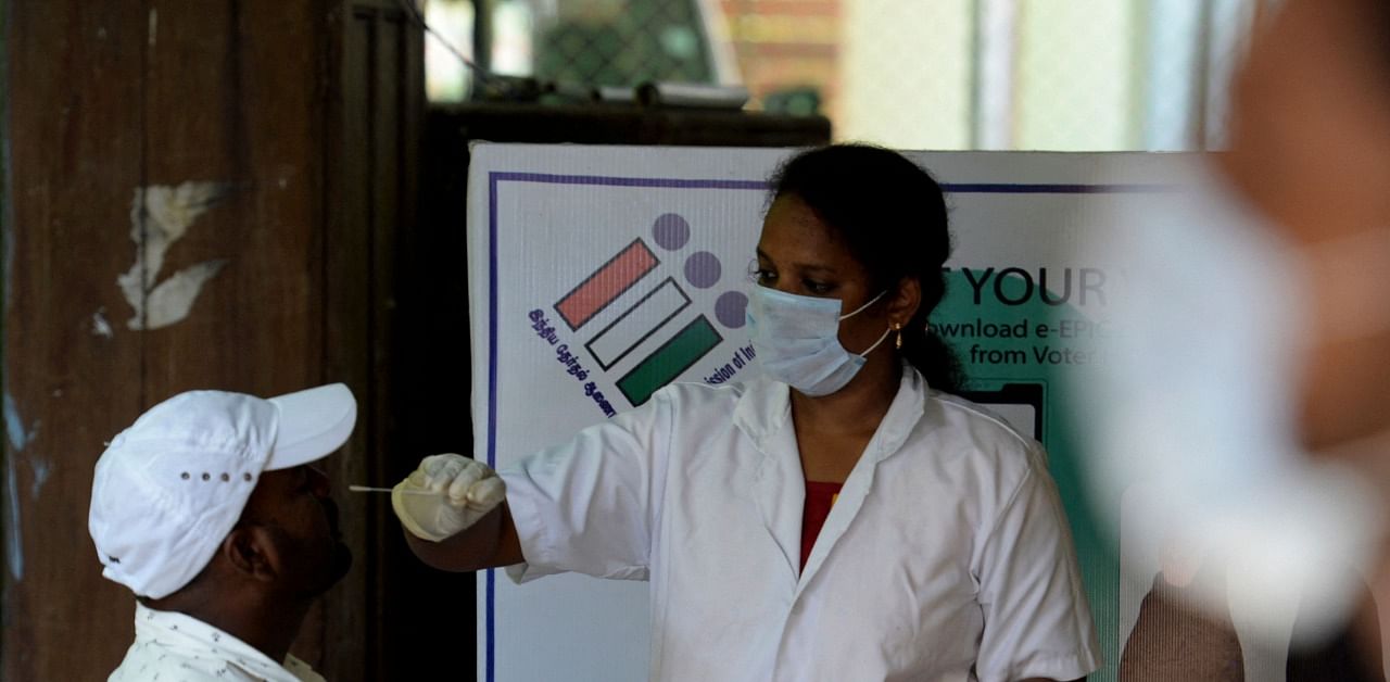 A health worker takes a swab sample from a man to conduct a RT-PCR test. Credit: AFP Photo