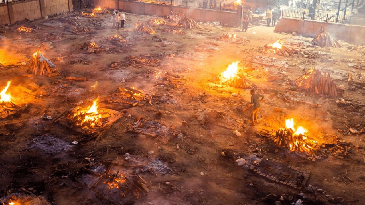 Men are seen around the burning pyres of victims who lost their lives due to the Covid-19 coronavirus at a cremation ground in New Delhi on April 26, 2021. Credit: AFP Photo