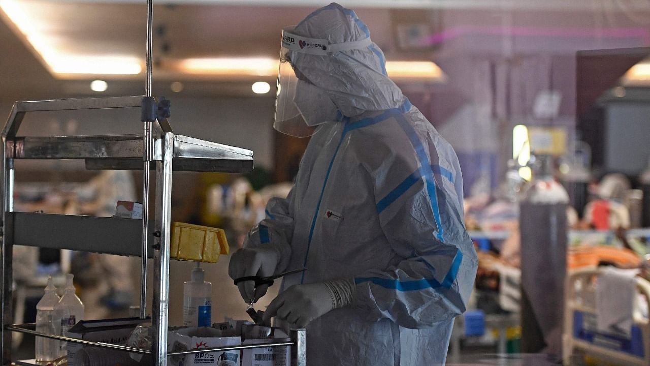 Health workers wearing personal protective equipment (PPE kit) attends to Covid-19 coronavirus positive patients inside a banquet hall temporarily converted into a covid care centre in New Delhi on April 29, 2021. Credit: AFP Photo