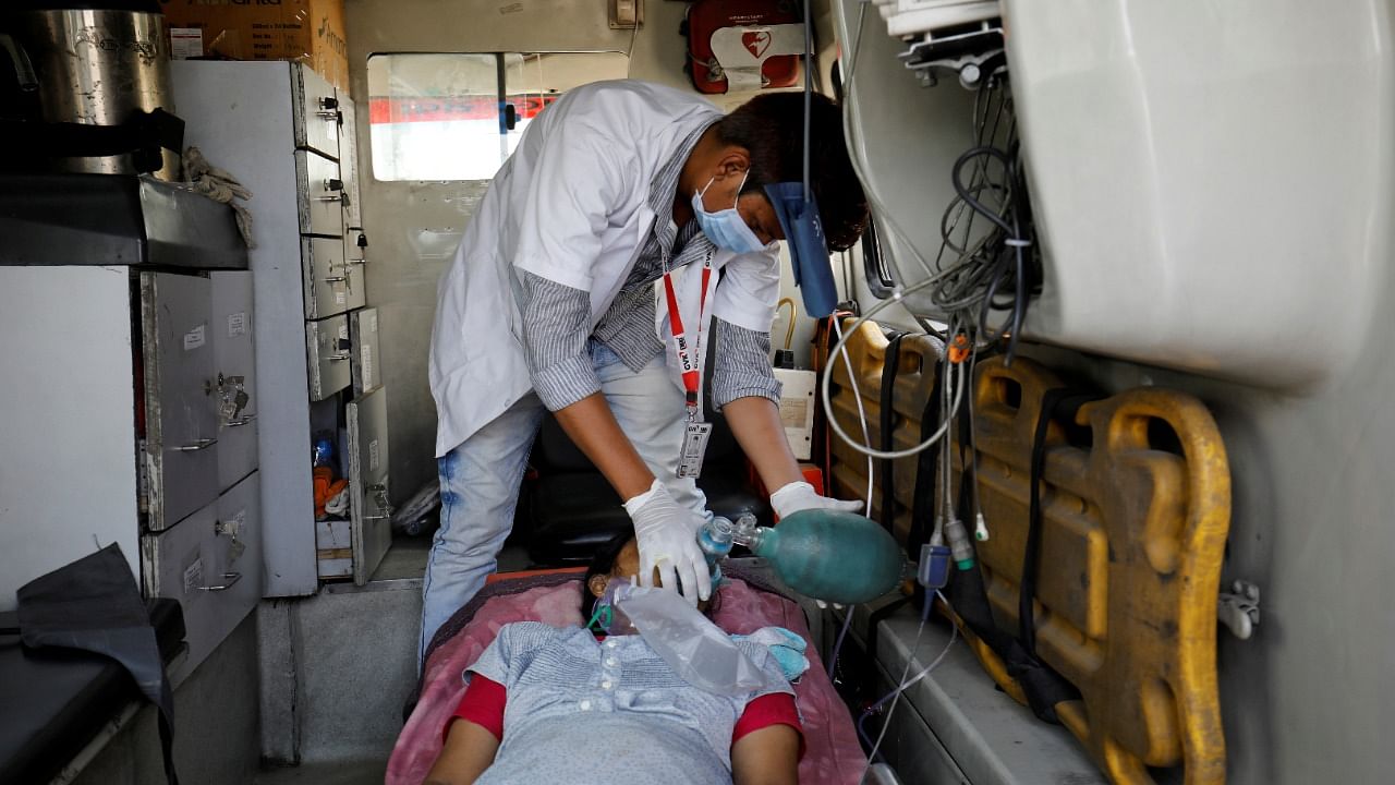 A paramedic adjusts an oxygen mask on a patient with breathing problems inside an ambulance waiting in a queue to enter a Covid-19 hospital in Ahmedabad. Credit: Reuters File Photo