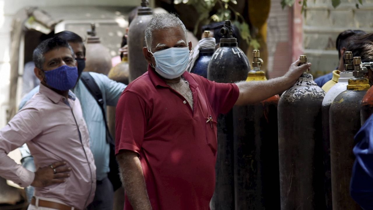 Family members of Covid-19 patients wait outside an oxygen-filling centre to refill their empty cylinders. Credit: PTI Photo