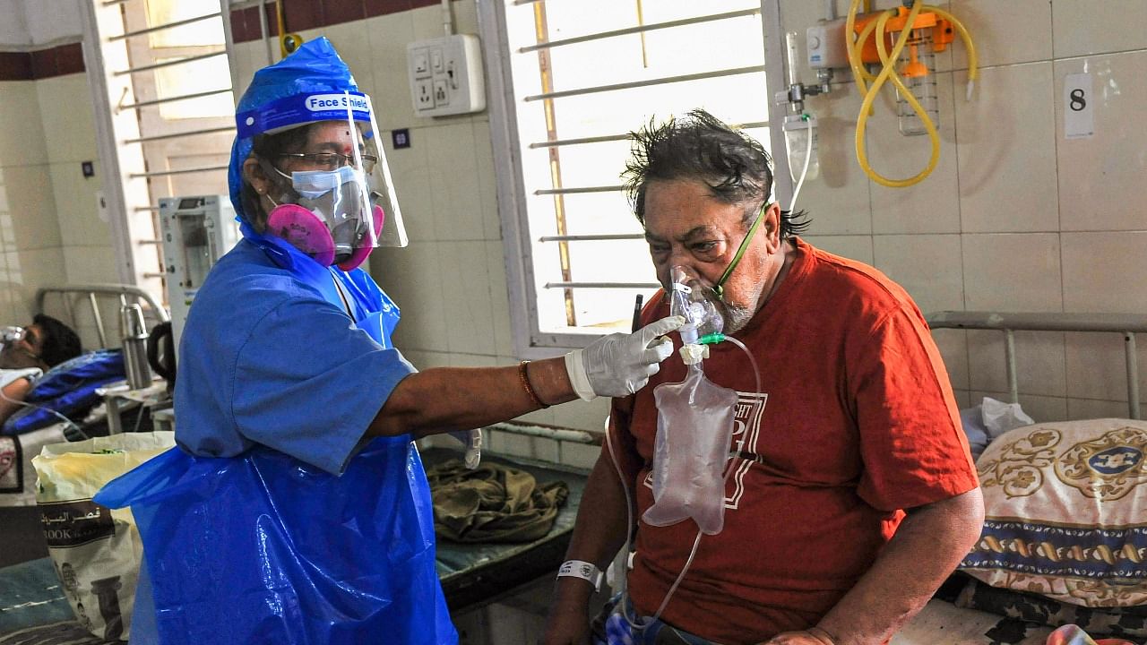 A health worker checks a Covid-19 patient on oxygen support at a hospital in Bengaluru. Credit: PTI Photo