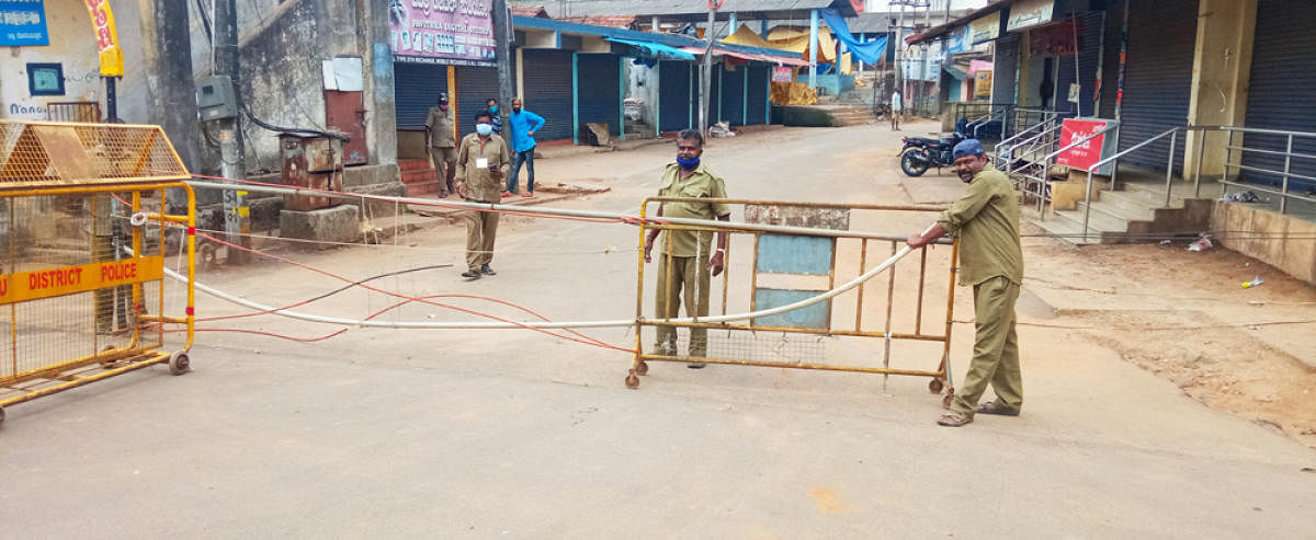 A civic worker places a barricade on the road leading to the shandy market in Suntikoppa.