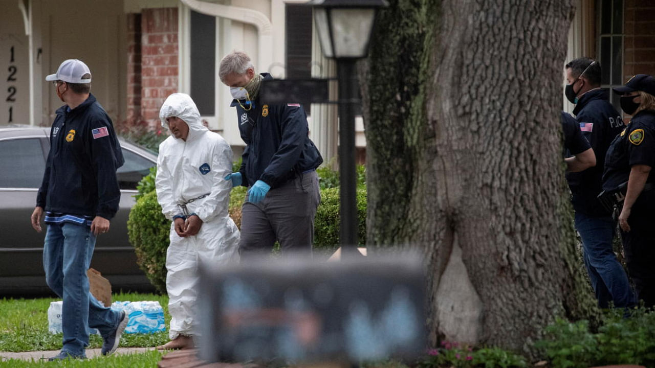 Homeland Security Investigations (HSI) personnel escort a man wearing handcuffs to a transport bus from a residence in southwest Houston. Credit: Reuters Photo