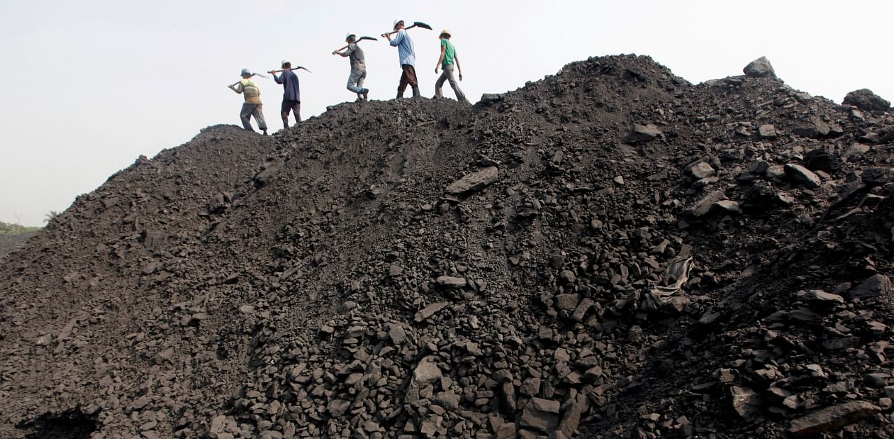 Workers walk on a heap of coal. Credit: Reuters Photo