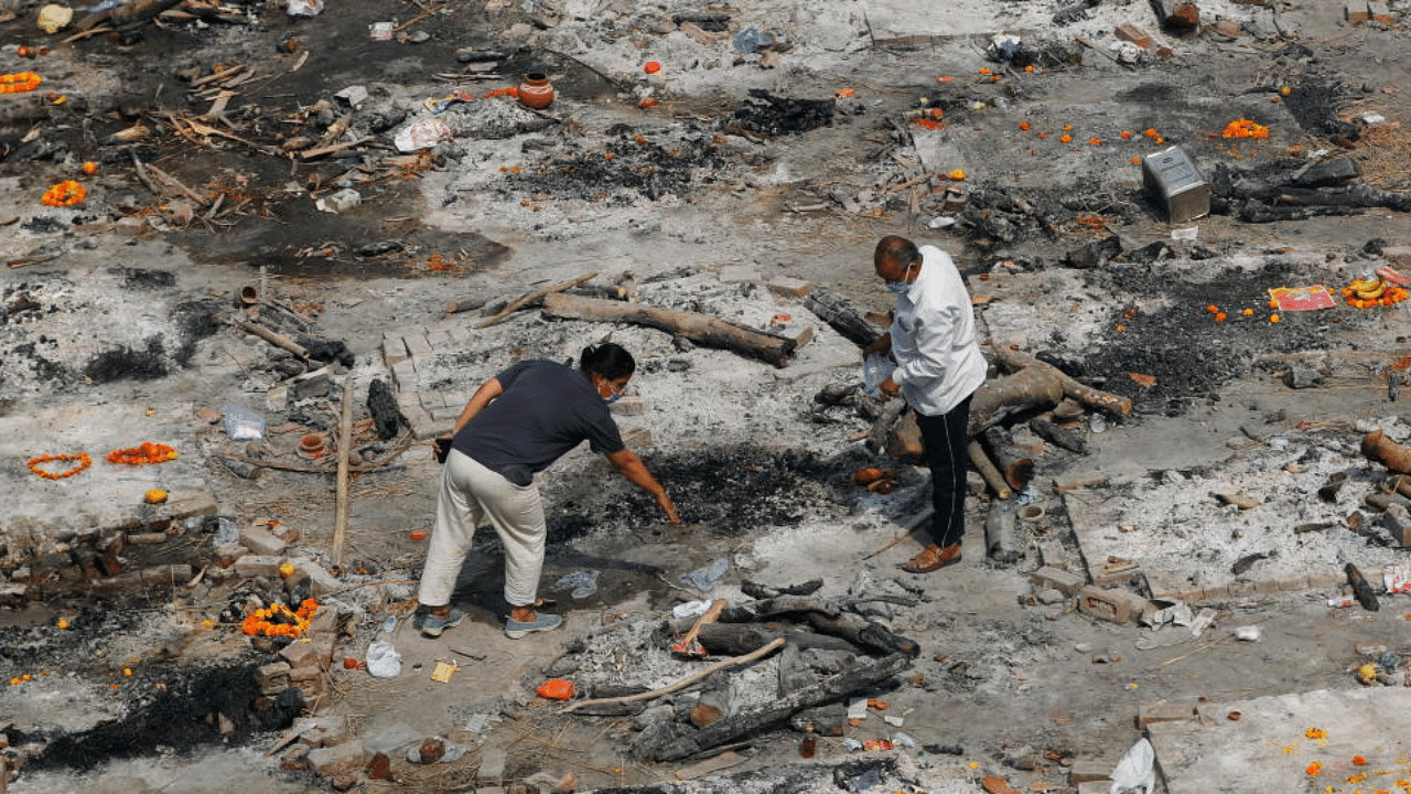 Relatives of a person who died from Covid-19 collect ashes at the spot where he was cremated in New Delhi. Credit: Reuters Photo