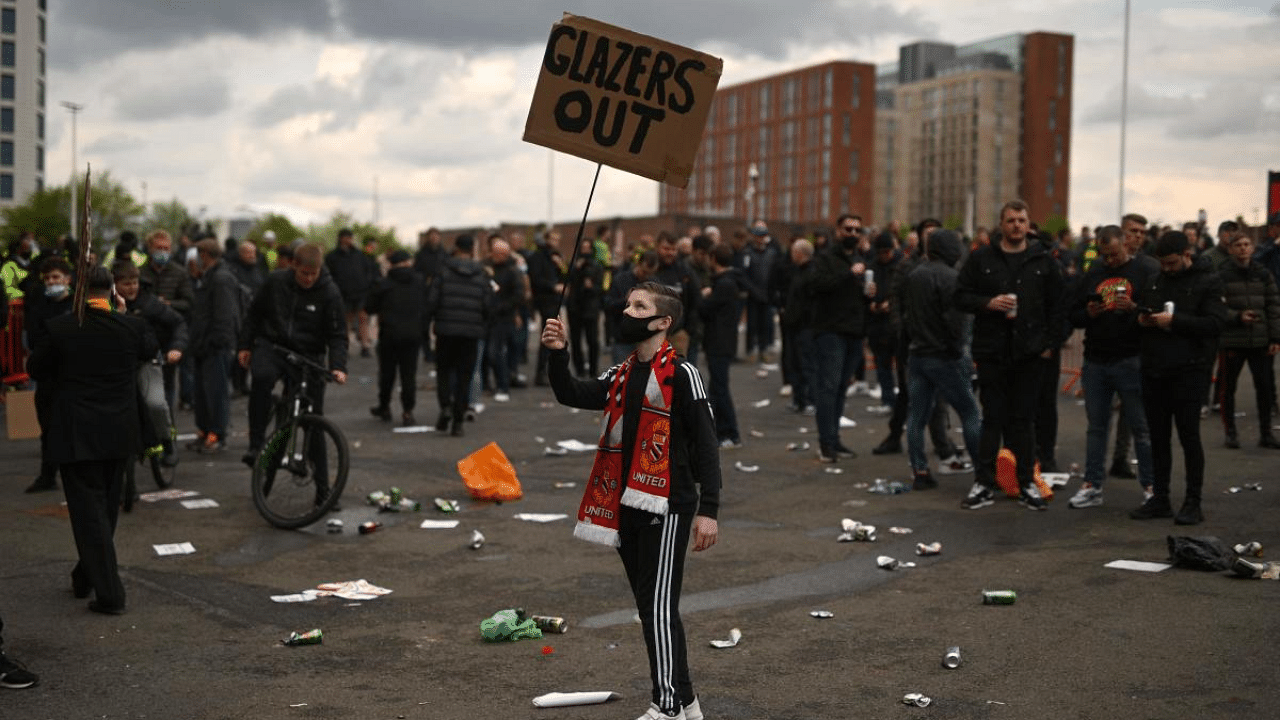 A young supporter holds up a placard during a supporter's protest against Manchester United's owners, outside Old Trafford Stadium. Credit: AFP Photo