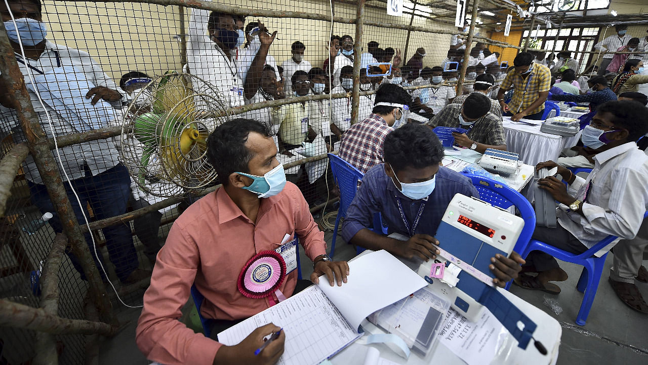 Election officials and agents of veinous political parties and independents candidates wearing face mask count vote for the Tamil Nadu Assembly polls at a counting centre at Loyola College, in Chennai. Credit: PTI Photo