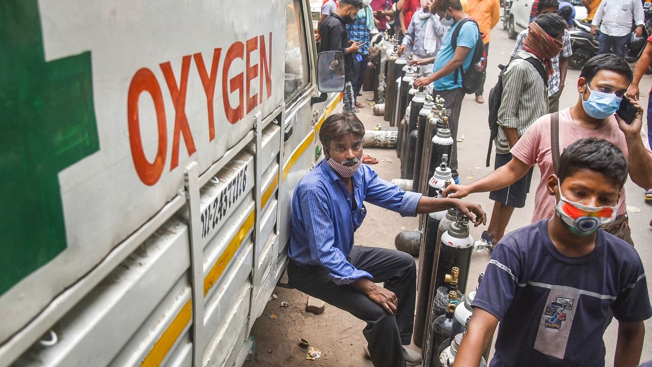 Family members of Covid-19 patients wait to fill their empty cylinders with medical oxygen outside an oxygen filling centre, at Bhogal, in New Delhi, Sunday, May 2, 2021. Credit: PTI Photo