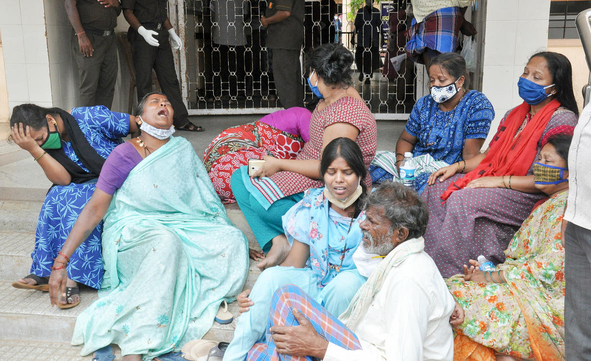 Family members of the deceased grieve at the District Covid Hospital in Chamarajanagar on Monday. DH Photo