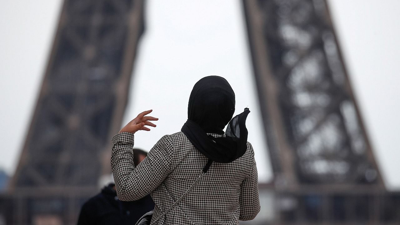 A woman wearing a hijab walks at Trocadero square near the Eiffel Tower in Paris, France. Credit: Reuters photo