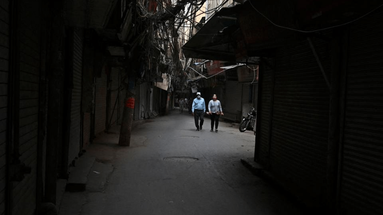 People walk along a deserted street past closed shops in the old quarters of New Delhi on May 5, 2021 as India's capital continues a lockdown imposed to curb the spread of the amid Covid-19 coronavirus.  Credit: AFP Photo