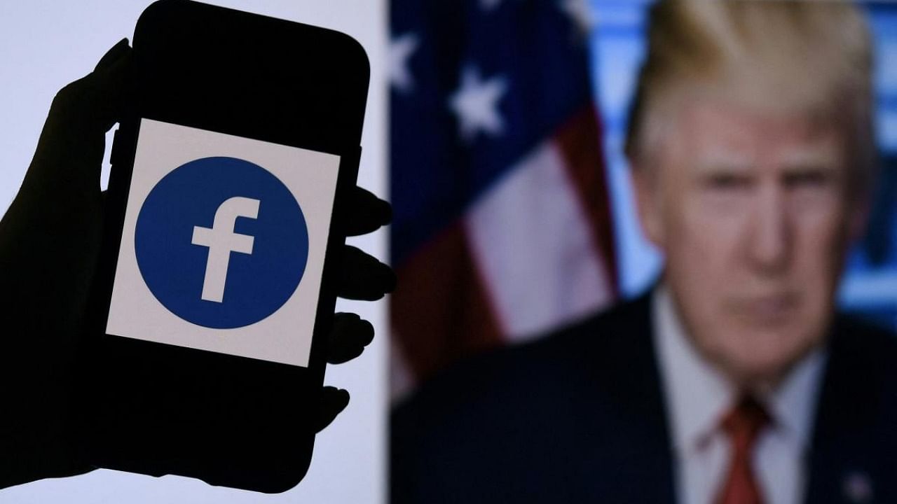 In this file photo illustration, a phone screen displays a Facebook logo with the official portrait of former US President Donald Trump on the background, on May 4, 2021, in Arlington, Virginia. Credit: AFP Photo
