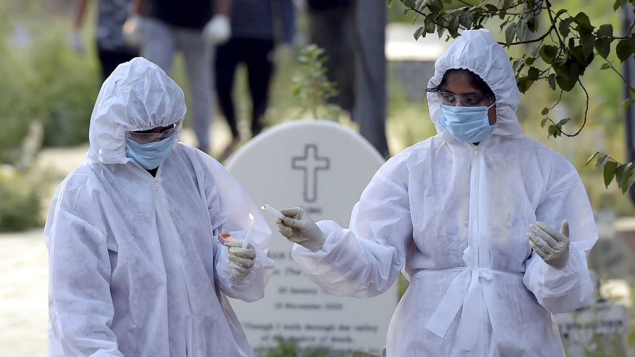 Family members perform the last rites of a person, who died from coronavirus, at a Christian cemetery in New Delhi, Monday, May 3, 2021. Credit: PTI Photo