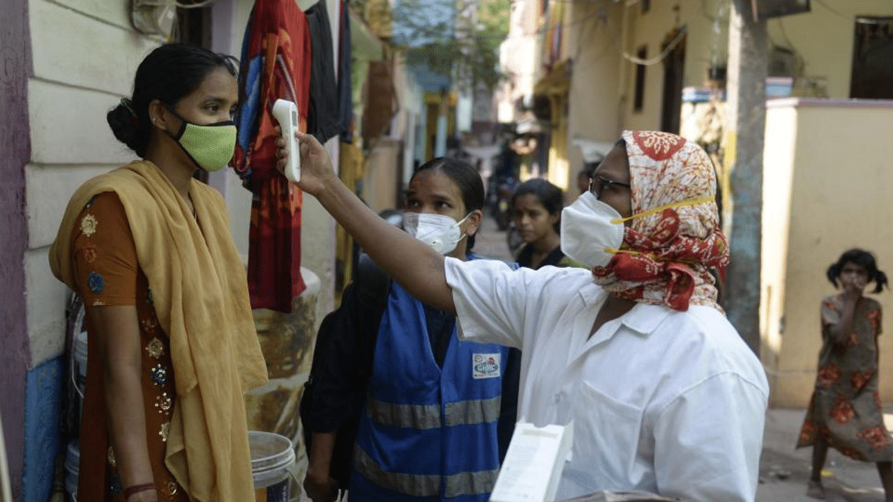 A health worker checks the body temperature of a woman during a door-to-door survey to monitor for Covid-19 coronavirus symptoms in residents of a low income neighbourhood in Hyderabad on May 6, 2021. Credit: AFP Photo