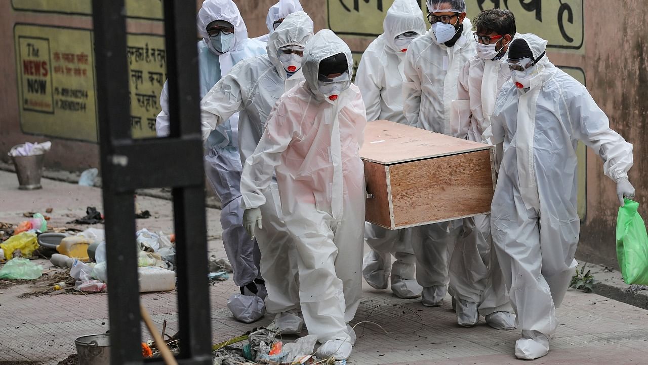 Health workers and family members, wearing protective suits, carry a Covid-19 victim for cremation, in Jammu. Credit: PTI photo