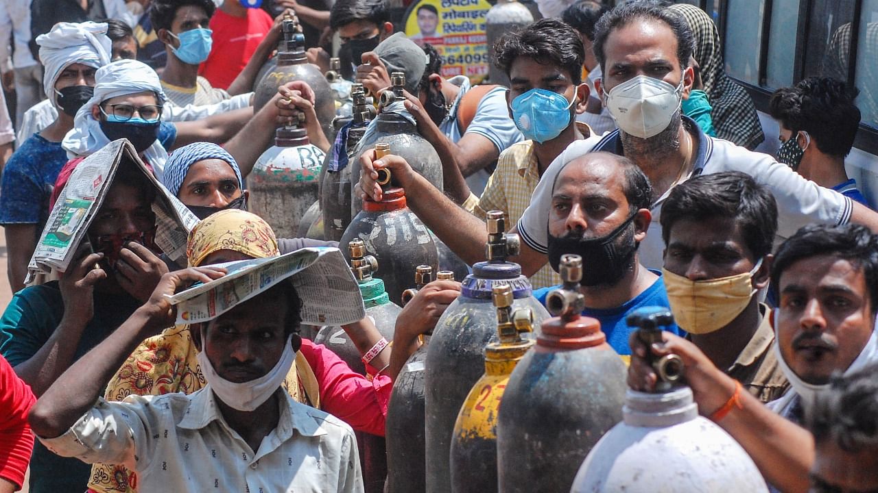 Family members of Covid-19 patients wait for their turn to refill empty oxygen cylinders, at a plant in Kanpur, Wednesday, May 5, 2021. Credit: PTI Photo