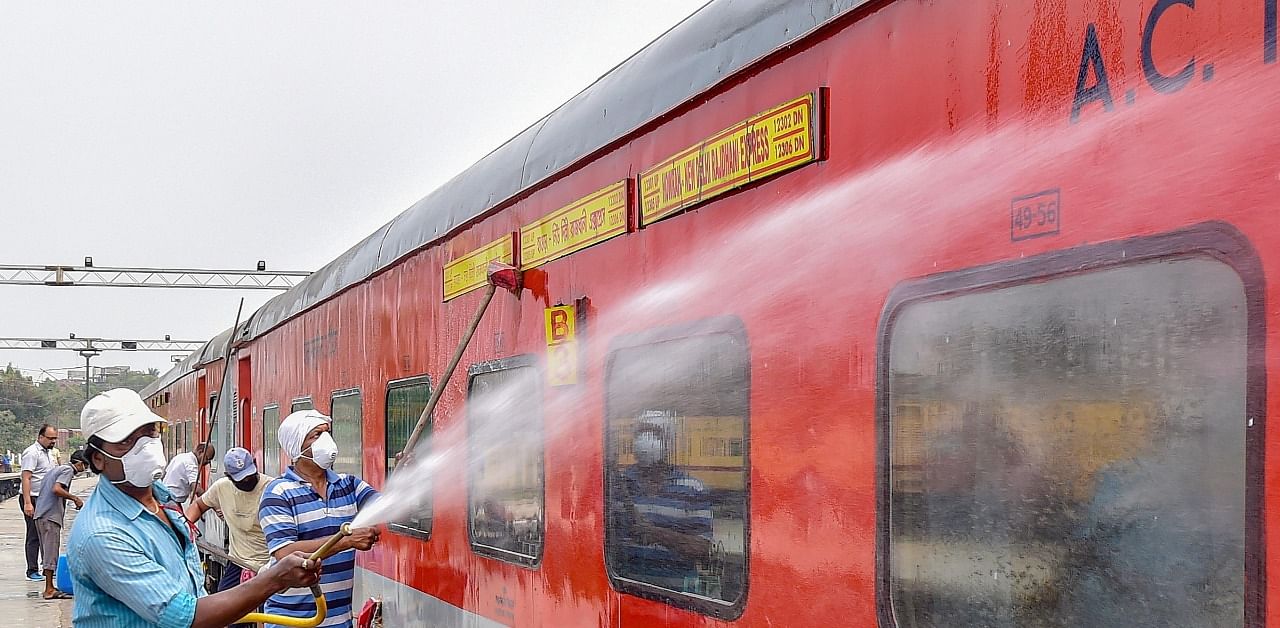 Railway workers spray disinfectant on Howrah-New Delhi Rajdhani Express. Credit: PTI Photo