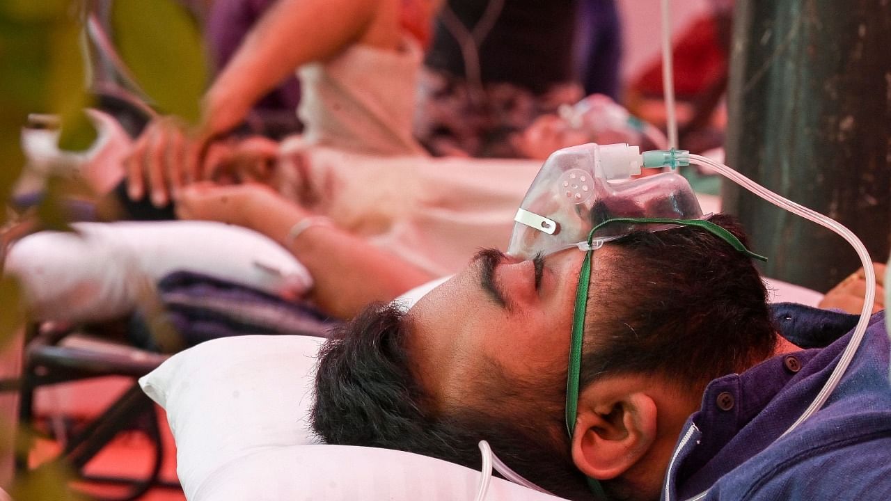 A Covid-19 patient breathes with the help of oxygen provided by a Gurdwara under a tent installed along the roadside in Ghaziabad. Credit: AFP Photo
