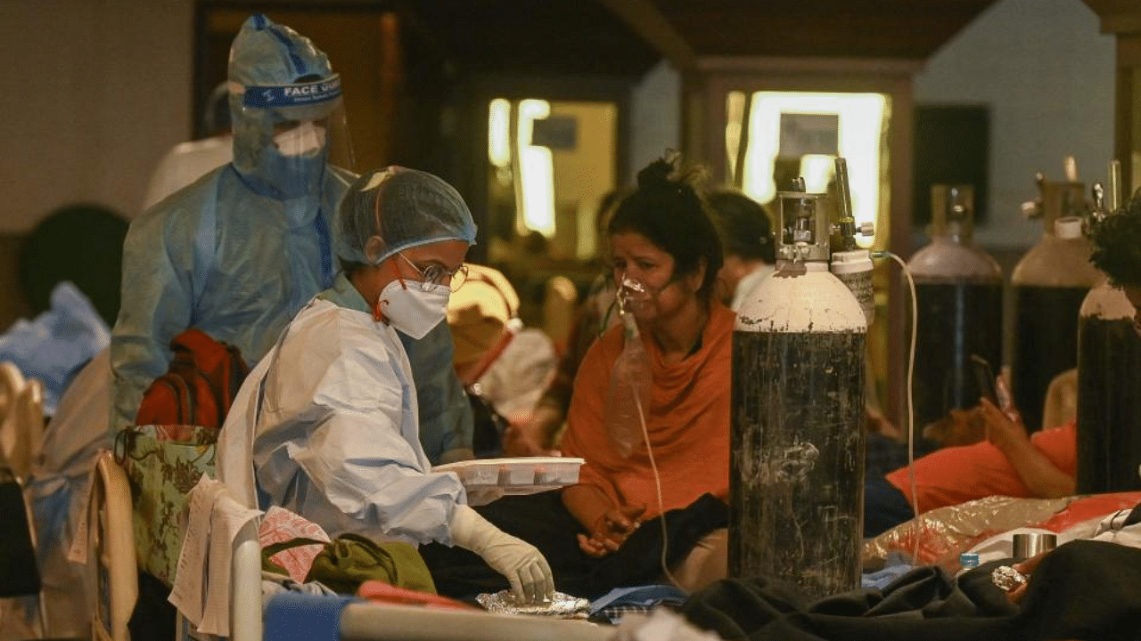 Health workers wearing personal protective equipment (PPE kit) attend to Covid-19 coronavirus patients inside a banquet hall temporarily converted into a Covid care centre in New Delhi on May 7, 2021. Credit: AFP Photo