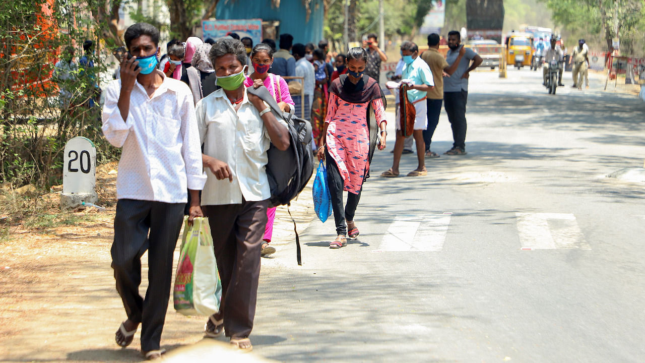 Passengers walk along a road after their bus was stopped at the Tamil Nadu-Andhra Pradesh border due to a lockdown in Andhra Pradesh imposed to curb the spread of Covid-19. Credit: PTI Photo