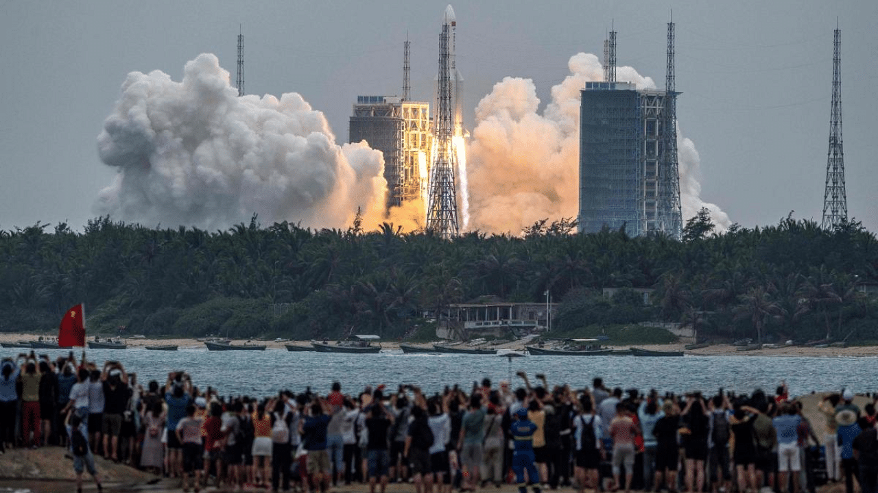 People watch a Long March 5B rocket, carrying China's Tianhe space station core module, as it lifts off from the Wenchang Space Launch Center. Credit: AFP File Photo