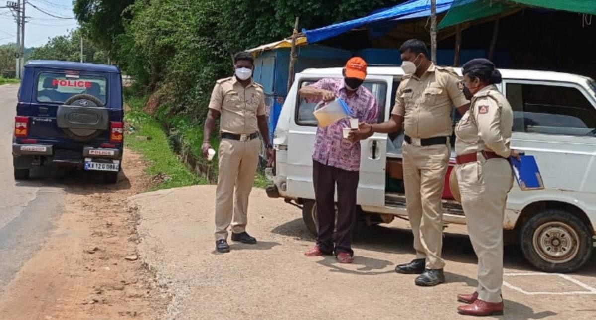 William serves juice to the police personnel at Vivekananda Circle in Somwarpet.